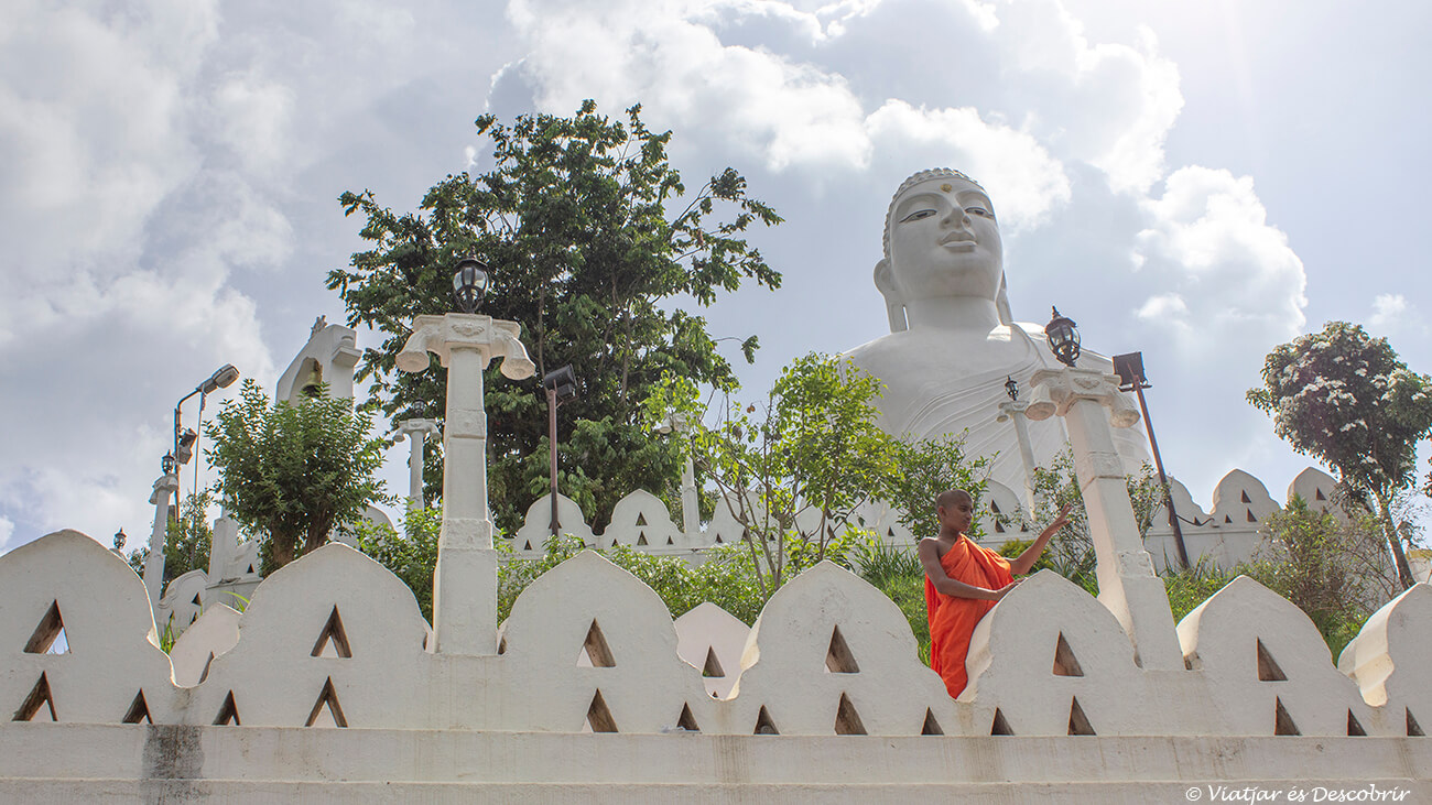 monje delante de la estatua de Buda de Bahiravokanda Vihara