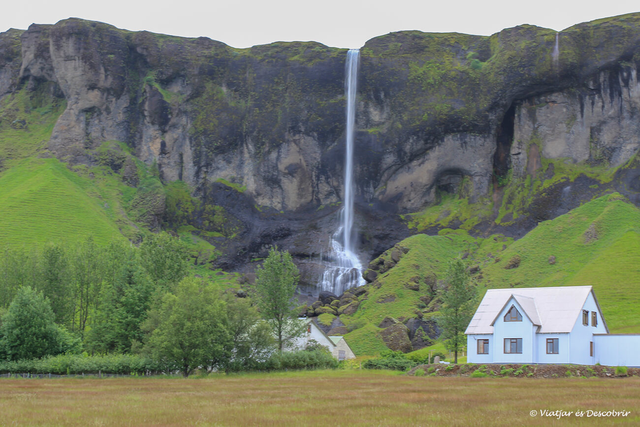 un vertical salt d'aigua i una petita casa blanca a prop del poble Kirkjubaejarklaustur