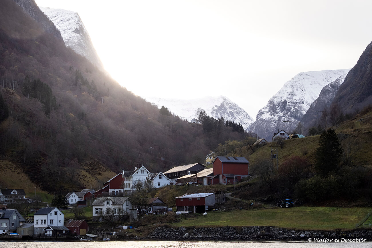 el poble de Undredal vist des de l'interior del fiord i amb el sol sobresortint entre les muntanyes
