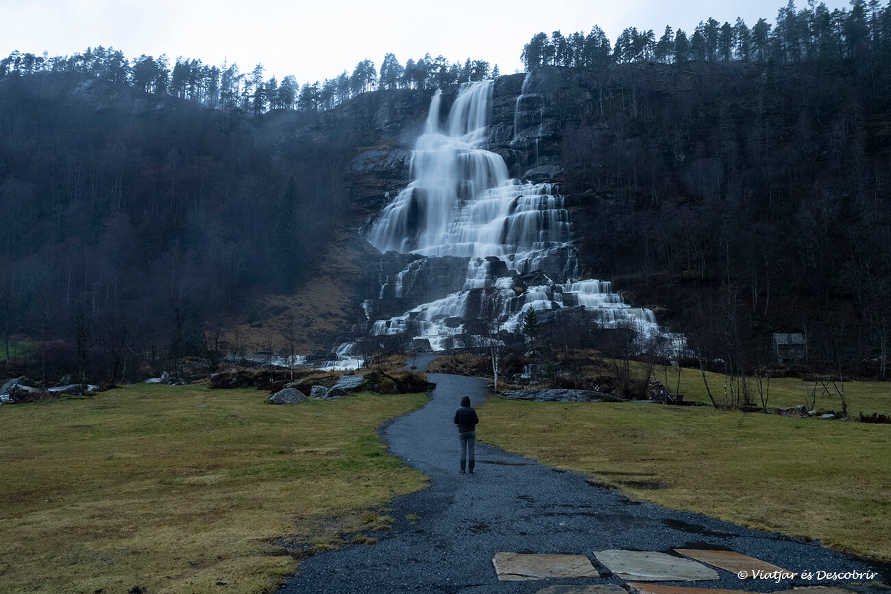 la cascada Tvindefossen i una persona a davant per veure les grans dimensions d'aquest salt d'aigua